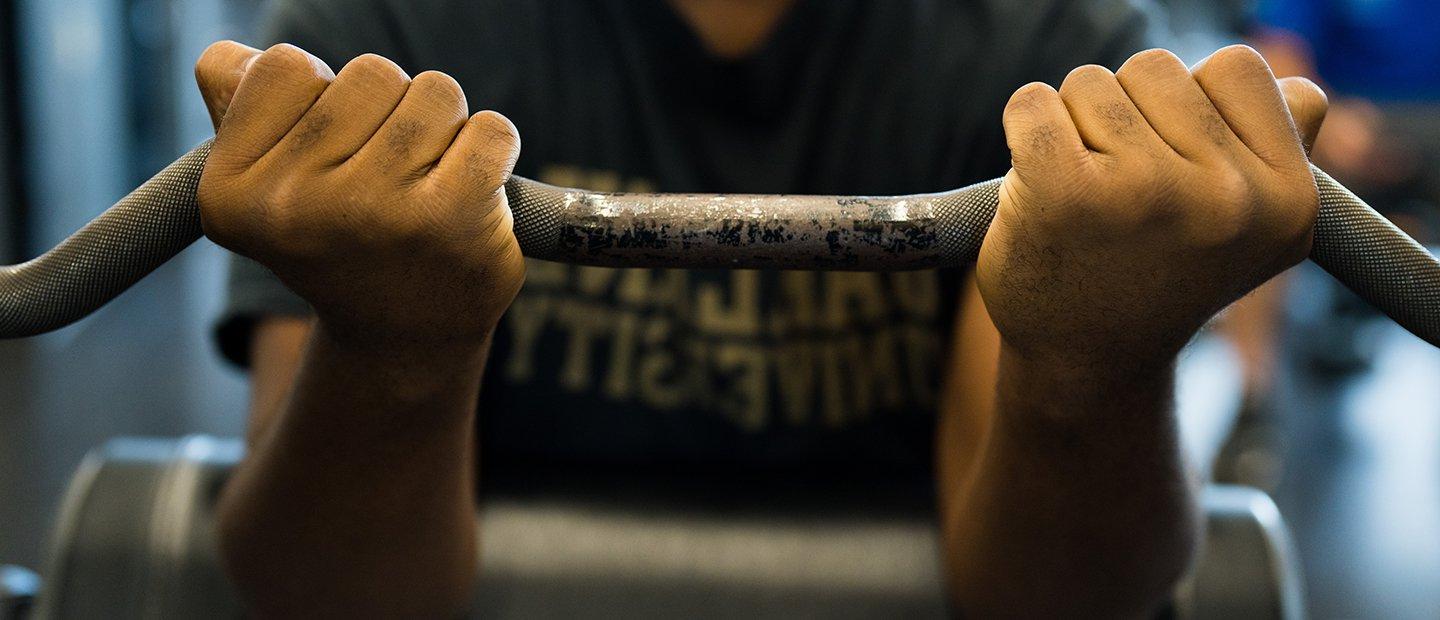 A person holding a barbell with an underhand grip.